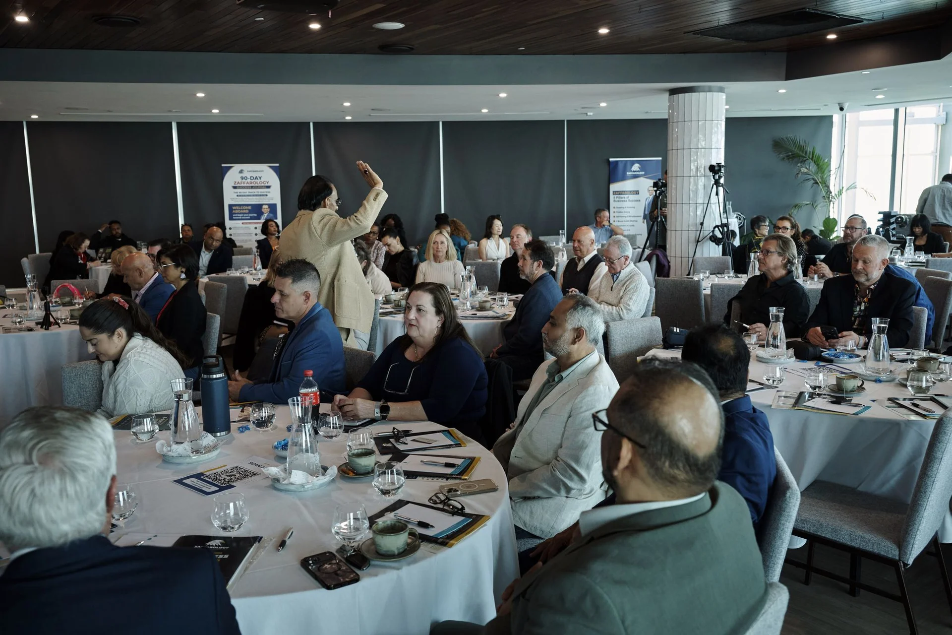 An attendee standing with her hand raised to ask a question from the floor