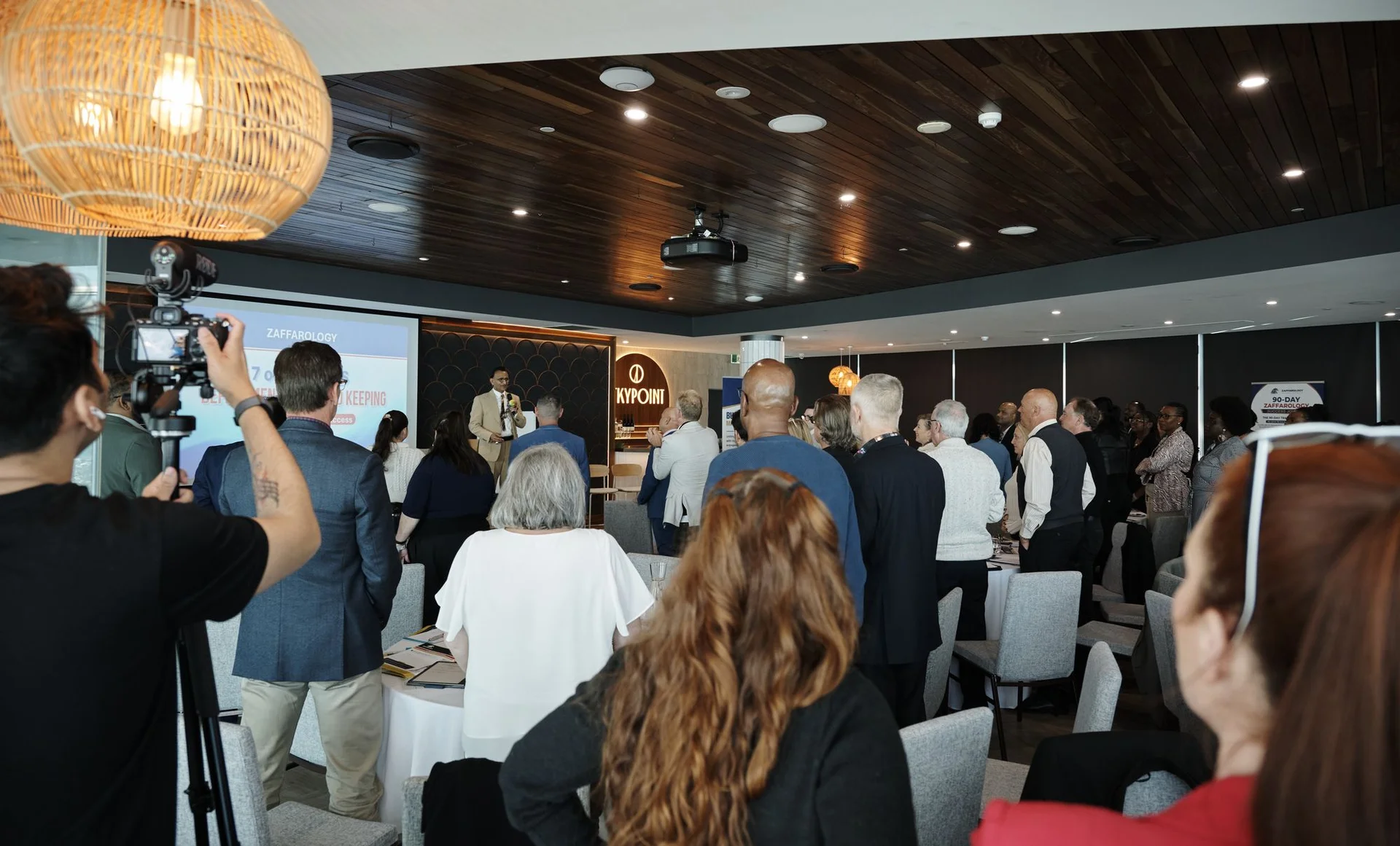 A videographer filming the room while attendees stand and mingle
